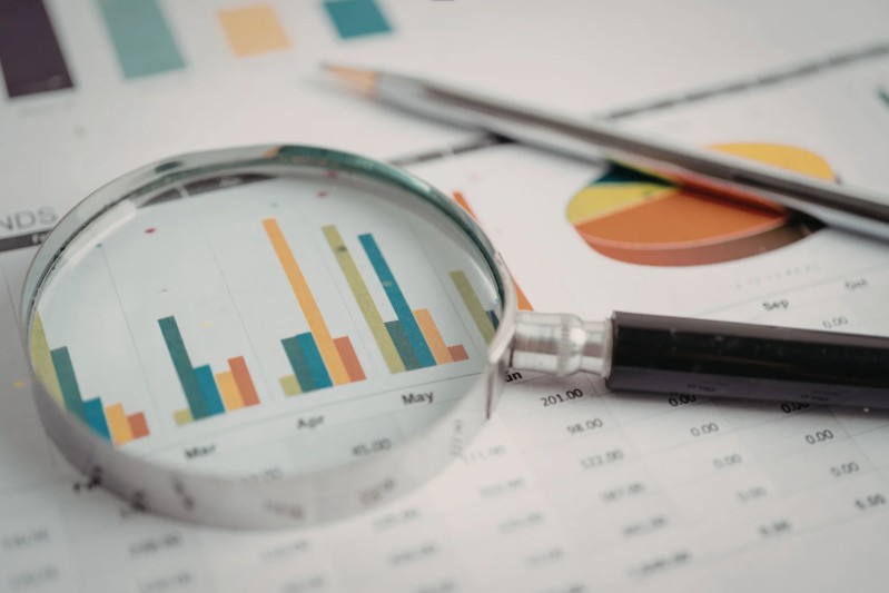 Magnifying glass highlighting a bar chart on a clean financial report with charts and tables.
