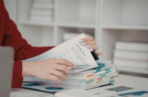 Person reviewing organized financial documents with a monthly goals sheet, calculator, and charts on a tidy office desk