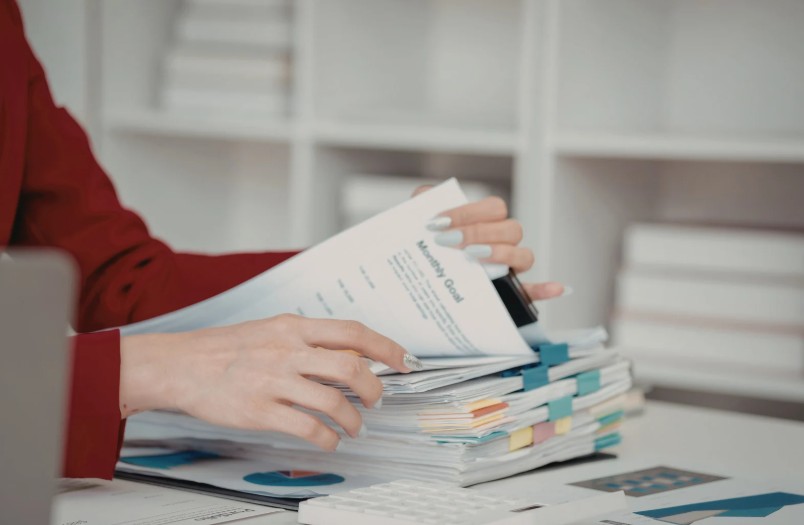 Person reviewing organized financial documents with a monthly goals sheet, calculator, and charts on a tidy office desk