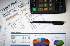 Balance sheet and financial reports laid out on a desk with a calculator and pen, illustrating financial analysis and structural review.
