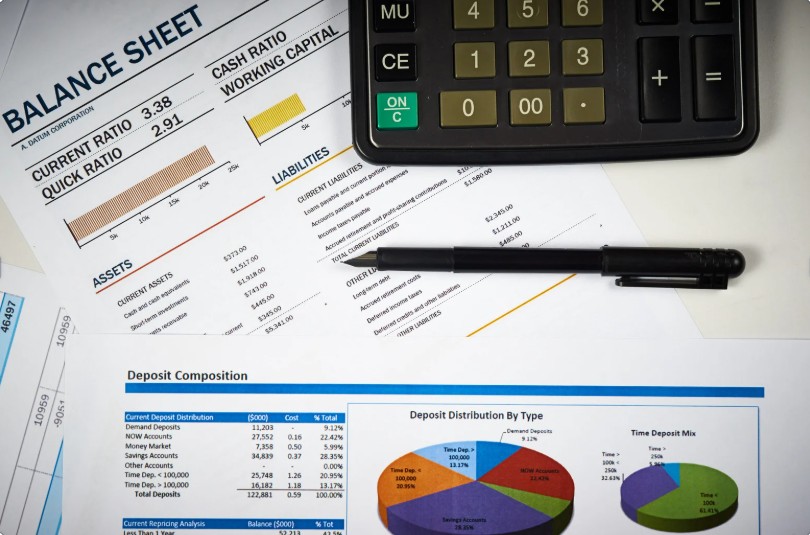 Balance sheet and financial reports laid out on a desk with a calculator and pen, illustrating financial analysis and structural review.