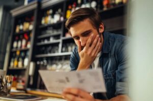 A business owner reviewing paperwork at a counter, focusing closely on financial details — representing the moment when numbers stop matching day‑to‑day reality.