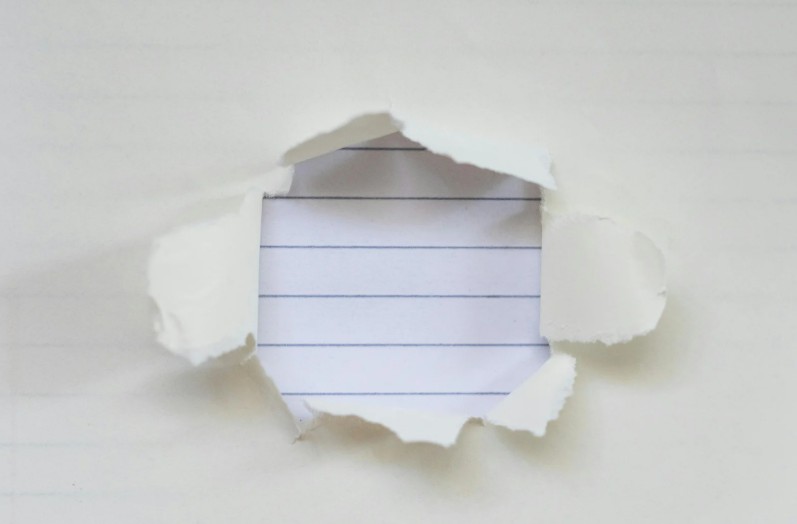 A sheet of paper torn open to reveal lined paper underneath, symbolizing missing or incomplete documentation.