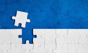 White puzzle with one missing piece on a blue background, representing a gap in an otherwise complete structure.